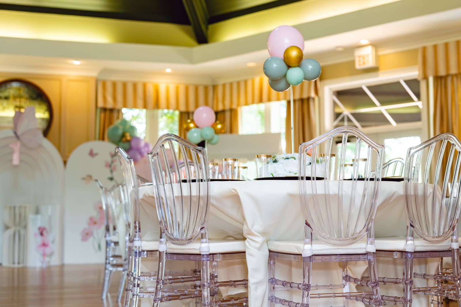 A styled dining room with ghost chairs, florals and a pastel balloon installation