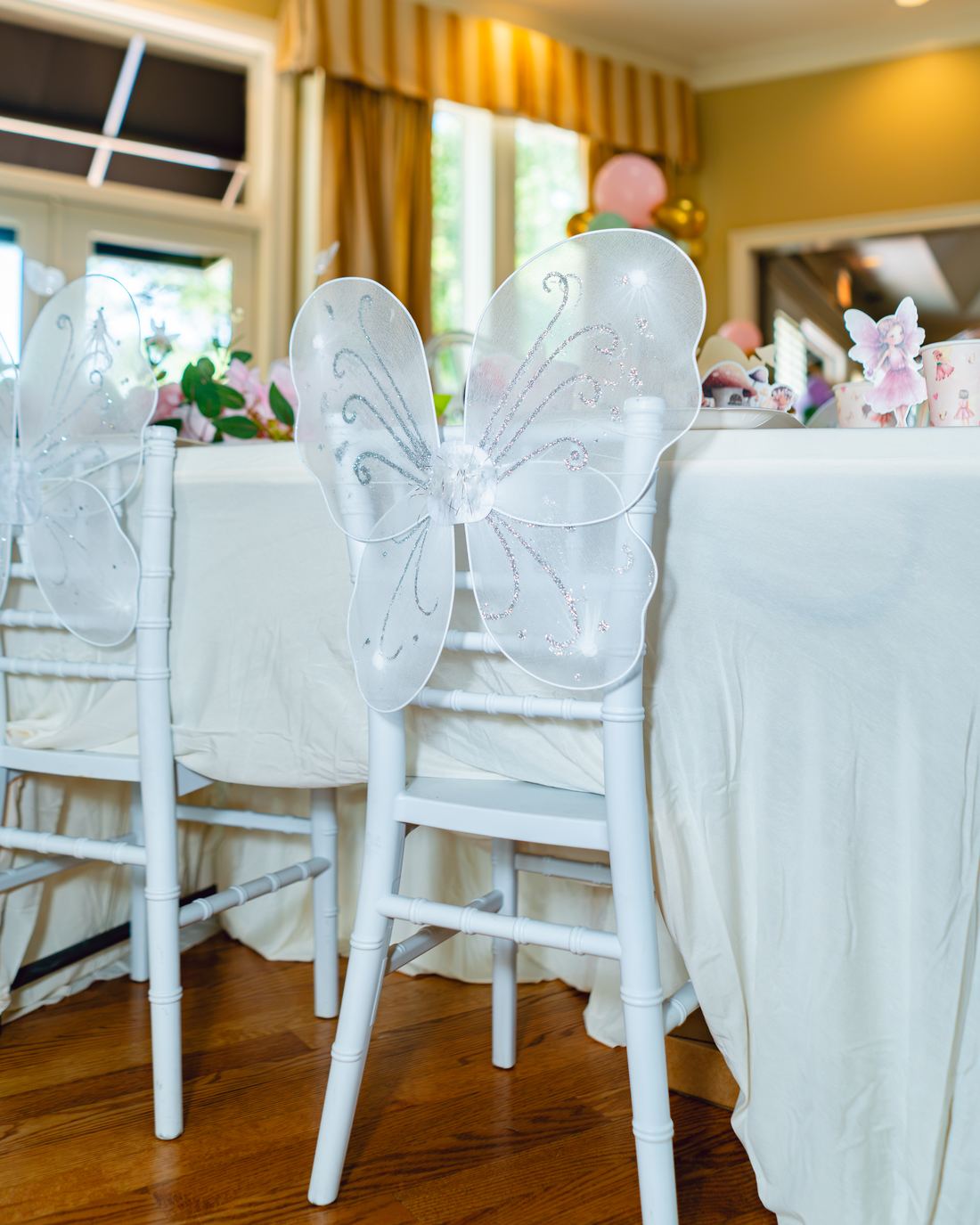 Fairy wings tied to the back of a white chiavari chair
