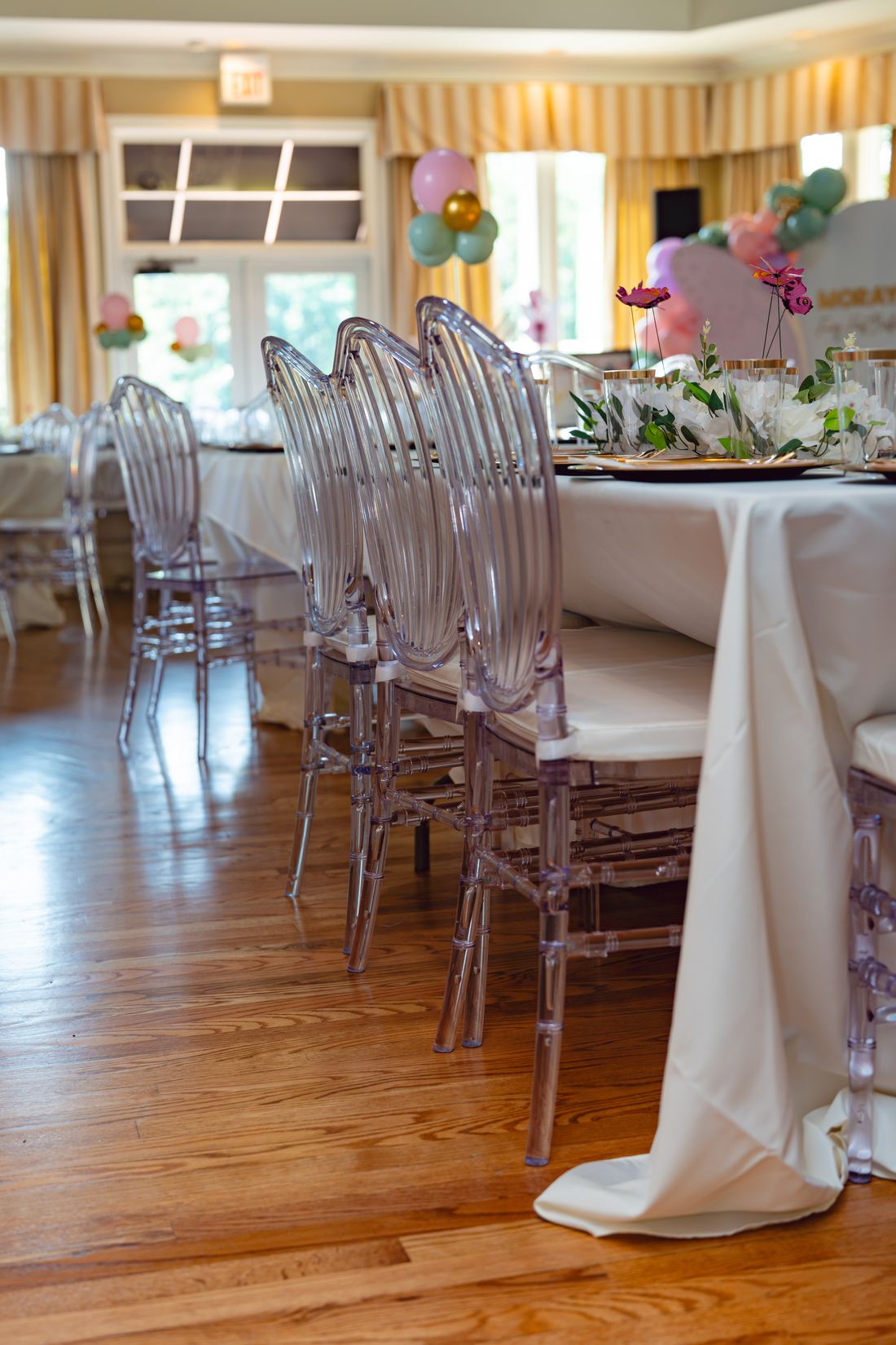 Banquet table lined with clear ghost chairs and white florals