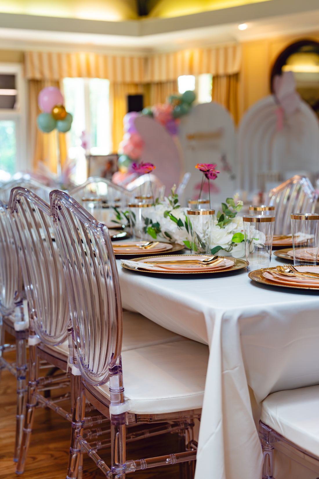 Banquet table dressed with white linen, gold chargers and florals