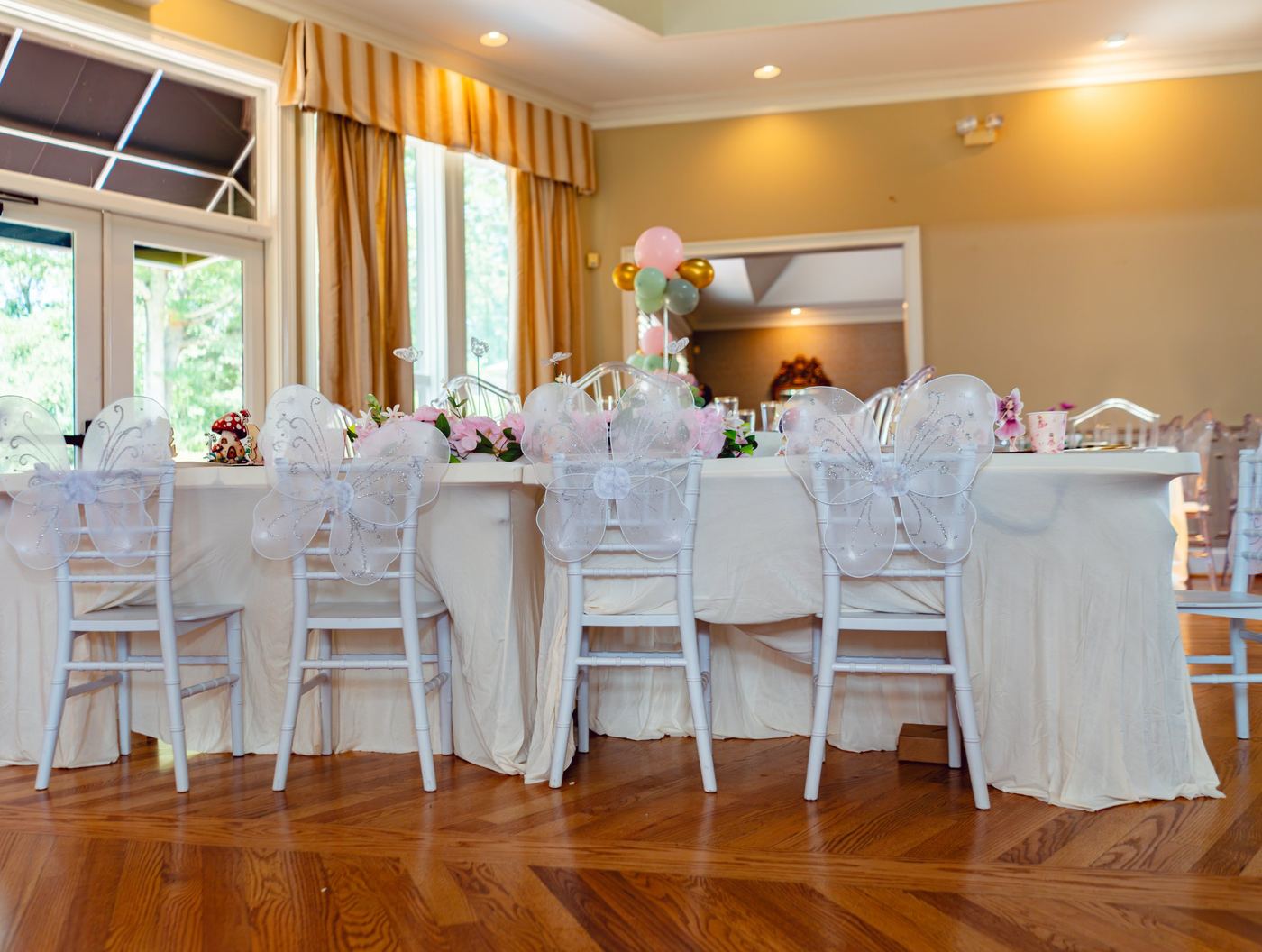 Long children's table with fairy wings on every chair and a floral runner