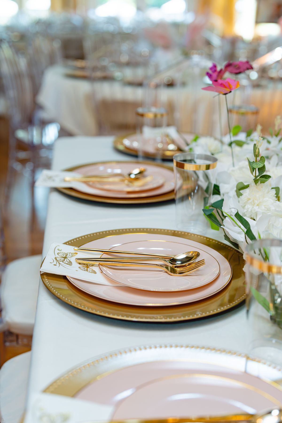 Blush and gold place setting with white florals and gold-rimmed glassware